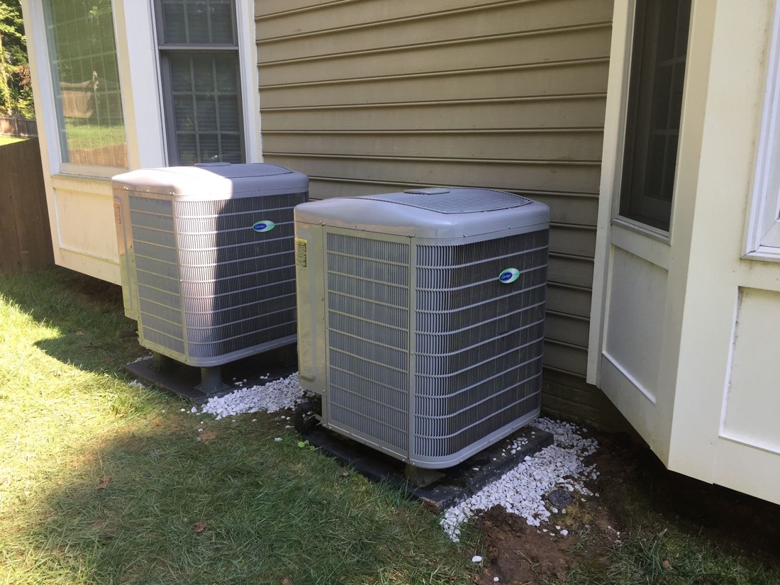 Two residential outdoor AC condenser units installed side by side