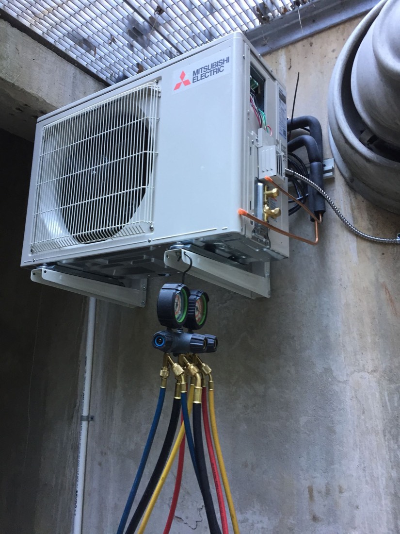 AIRSOURCE technician servicing a Mitsubishi Electric outdoor unit